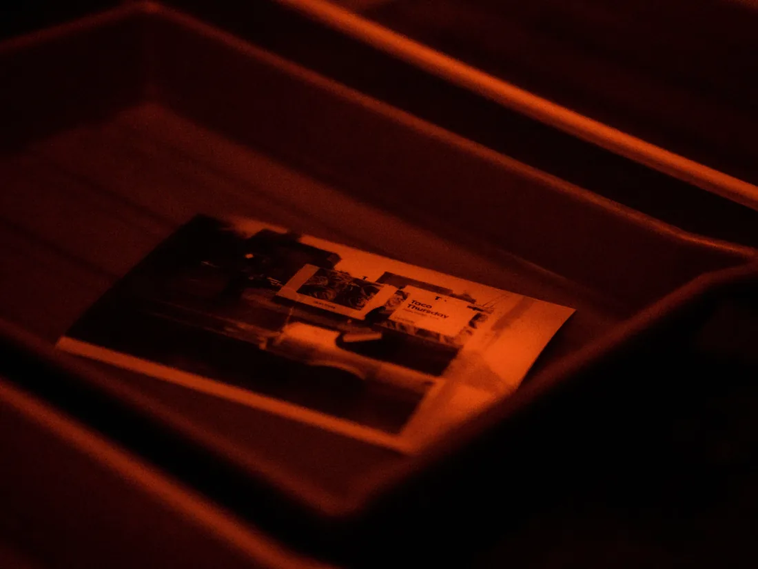 Fotografie ve vývojce v misce temné komory pod tlumeným červeným světlem